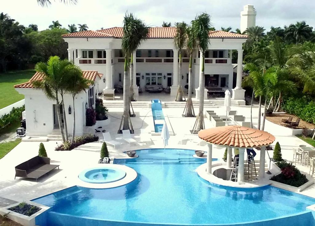 An estate with a peach clay tile roof and pool